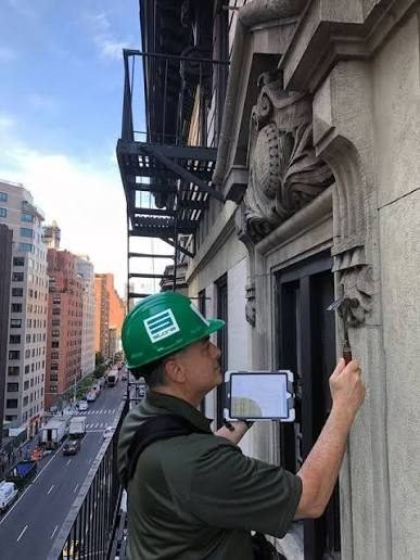 Inspector sounding a stone facade on a fire escape